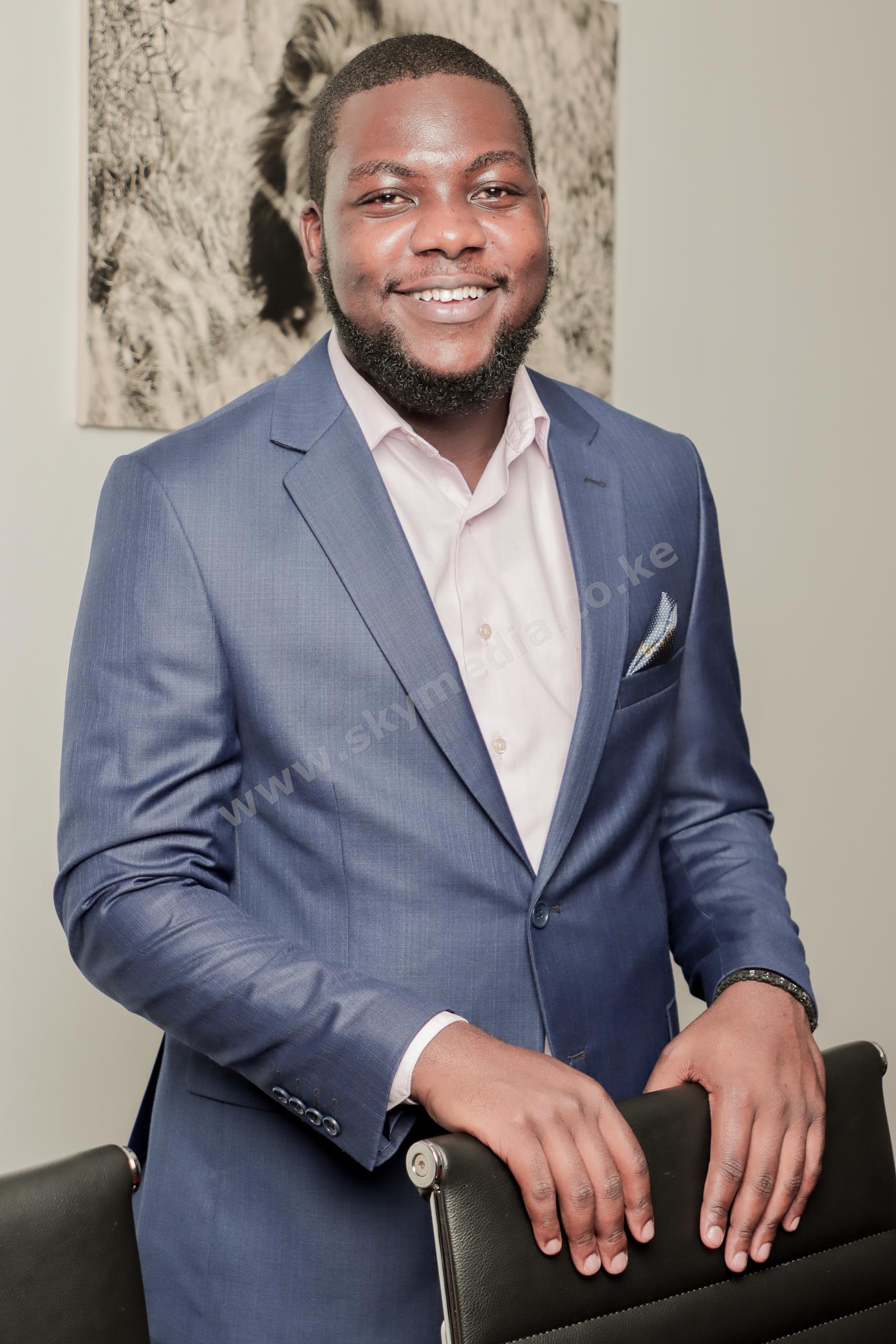 Professional corporate headshot of a smiling man in a blue suit