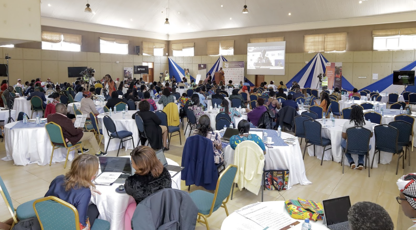 Wide shot of attendees seated at tables in a large corporate workshop